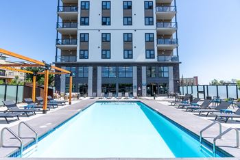 A large swimming pool in front of a multi-story apartment building.